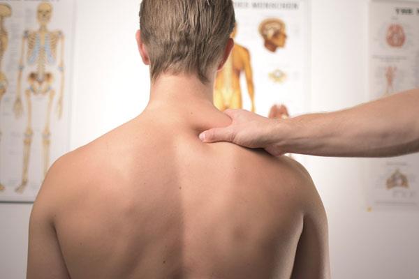 treating upper back pain with massage on man sitting up