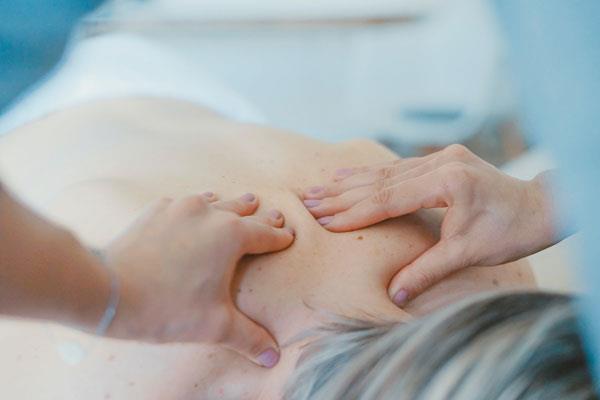 massaging upper back pain between shoulder blades on elderly woman